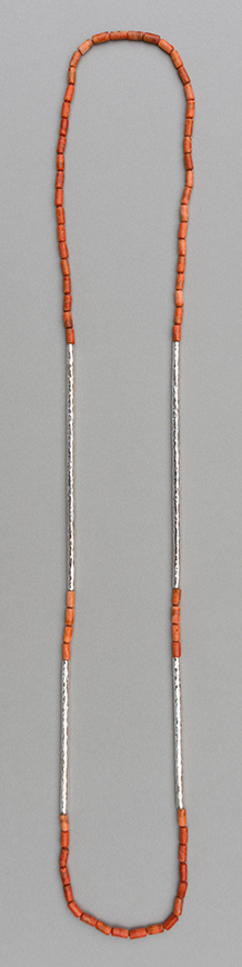 A necklace with six paired hammered 925 silver tubes in different lengths combined with apple coral tubes.Necklace Two pairs of hammered 925 silver tubes of different length combined with apple coral tubes
