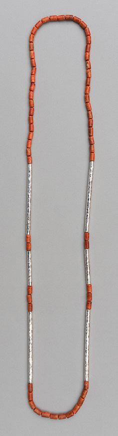 A necklace with six paired hammered 925 silver tubes in different lengths combined with apple coral tubes