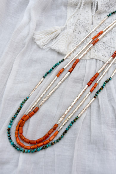 A series of hammered tube necklaces interlaced with either turquoise or apple coral